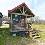 The Coyote P-561SL by Platinum Cottages and RRC Athens. this display model cabin features a front porch, large loft, stained exterior, and Blue Ponderosa pine accents throughout